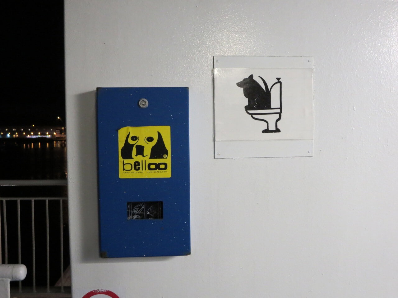 Ein Schild mit einem Hund auf einer Toilette und eine Box mit Abfallbeuteln für das Geschäft