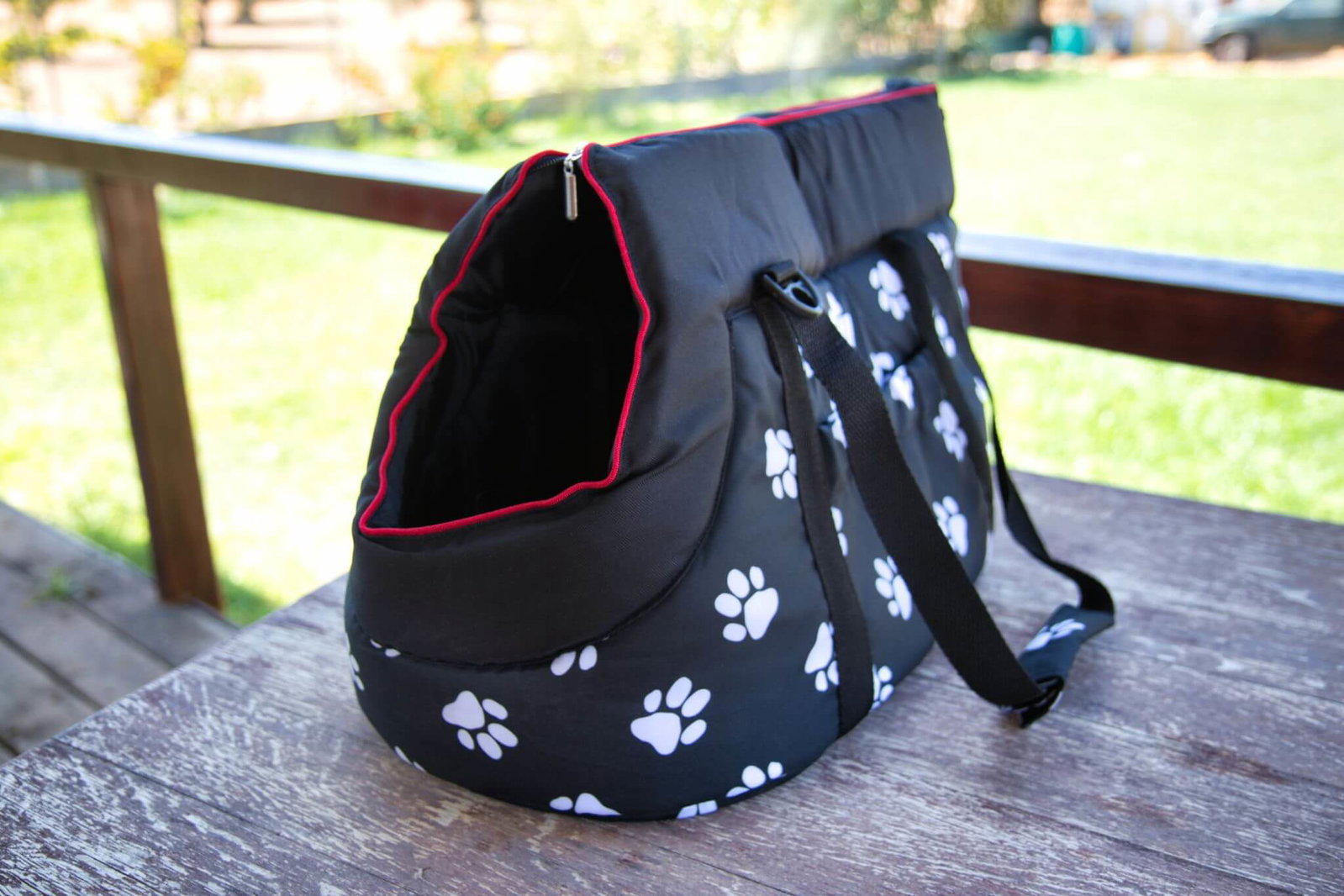 Unsere getestete Hundetragetasche von Hobbydog ist aus Polyester, schwarz mit weißem Pfotendruck und roten Nähten.