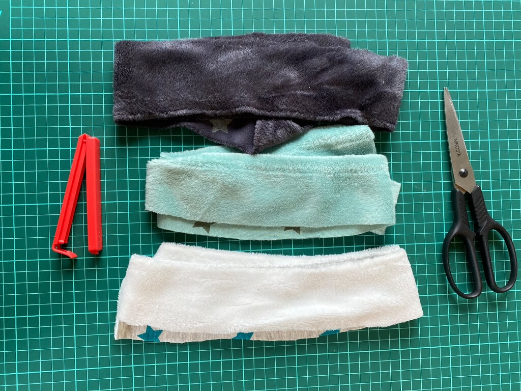 3 Stoffstreifen, eine Klammer und eine Schere