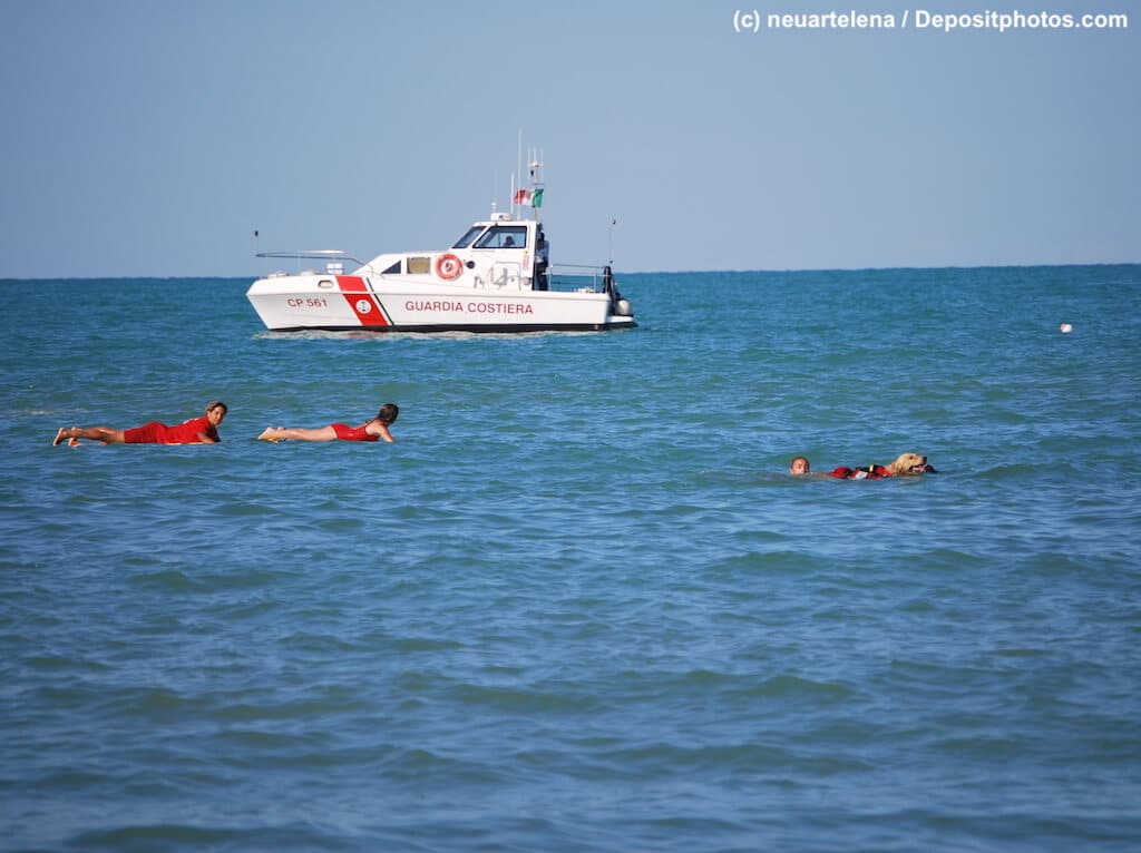 Rettungsschwimmer mit Schiff und Hund im Meer.