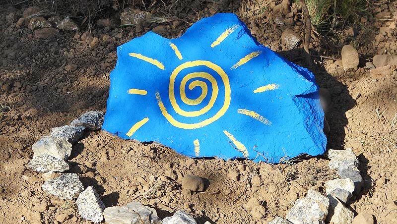 Ein blauer Stein, auf den eine gelbe Sonne gemalt ist
